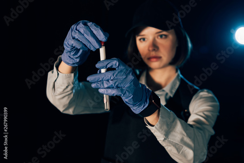 selective focus of investigator in rubber gloves holding swab and test tube at crime scene photo