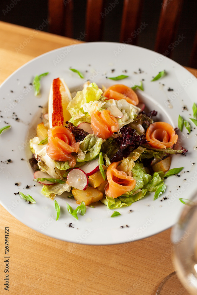 Fresh trout salad with greens and herbs on a white plate Fresh trout salad with greens and herbs on a white plate