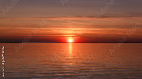 Beautiful sunset over the sea. The sun sets on the water. The sky is painted with bright colors. Sunset beach in a summer evening. Gulf of Finland, Baltic sea, Kronstadt, Saint-Petersburg, Russia.