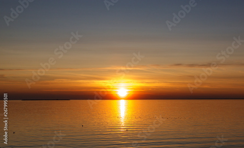 Beautiful sunset over the sea. The sun sets on the water. The sky is painted with bright colors. Sunset beach in a summer evening. Gulf of Finland, Baltic sea, Kronstadt, Saint-Petersburg, Russia.