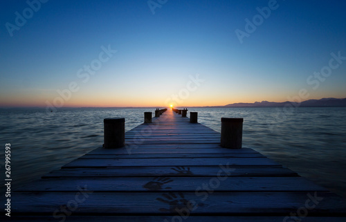 Fototapeta Naklejka Na Ścianę i Meble -  Langer Holzsteg, am Horizont die aufgehende Sonne