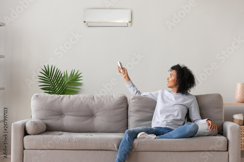 Smiling African American woman using air conditioner remote controller photo