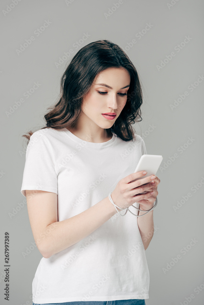 concentrated young girl in white t-shirt using smartphone isolated on grey concentrated young girl in white t-shirt using smartphone isolated on grey