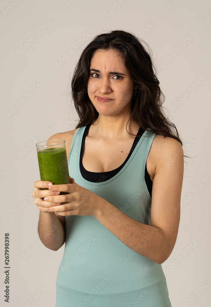 Beautiful young sports latin woman boring of diet holding green smoothie in dislike Beautiful young sports latin woman boring of diet holding green smoothie in dislike