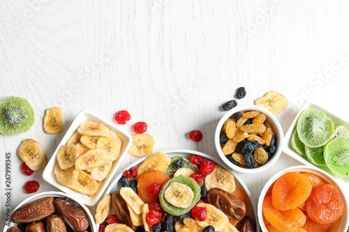 Fototapeta Naklejka Na Ścianę i Meble -  Bowls of different dried fruits on wooden background, top view with space for text. Healthy lifestyle