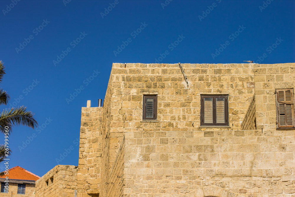 Eastern Arabic architecture building yellow brick wall facade with windows on blue sky background 