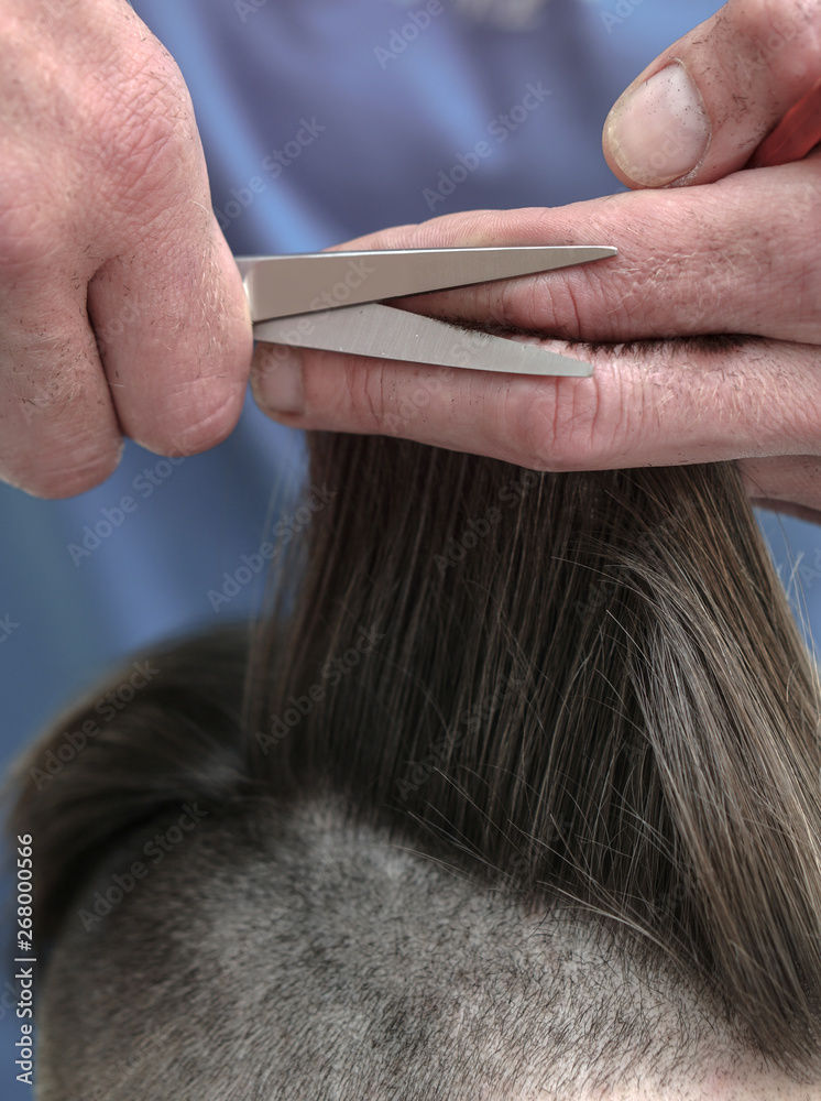 Fototapeta premium Haircutting process in the hairdresser. man in the salon smoothes his hair. Hands with scissors. Stock photos for design