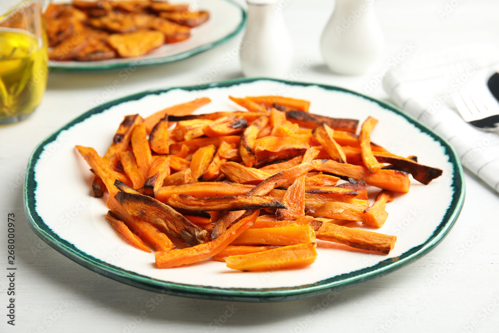 Plate with baked sweet potato slices on table, closeup