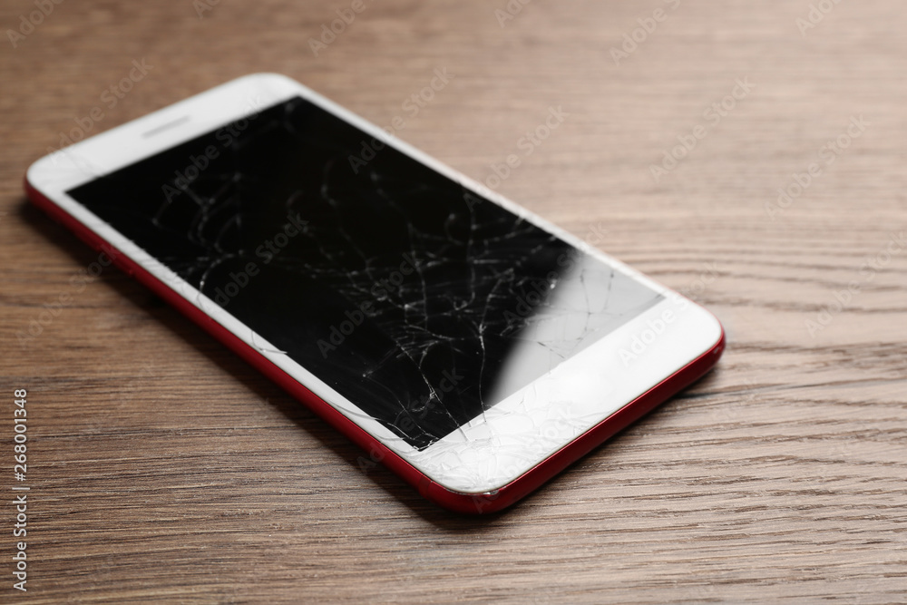 Modern smartphone with broken display on table. Device repair service Modern smartphone with broken display on table. Device repair service