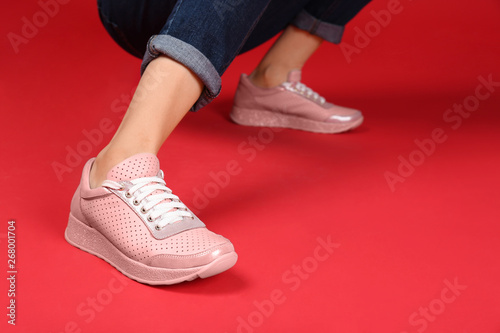Woman in stylish sport shoes on color background