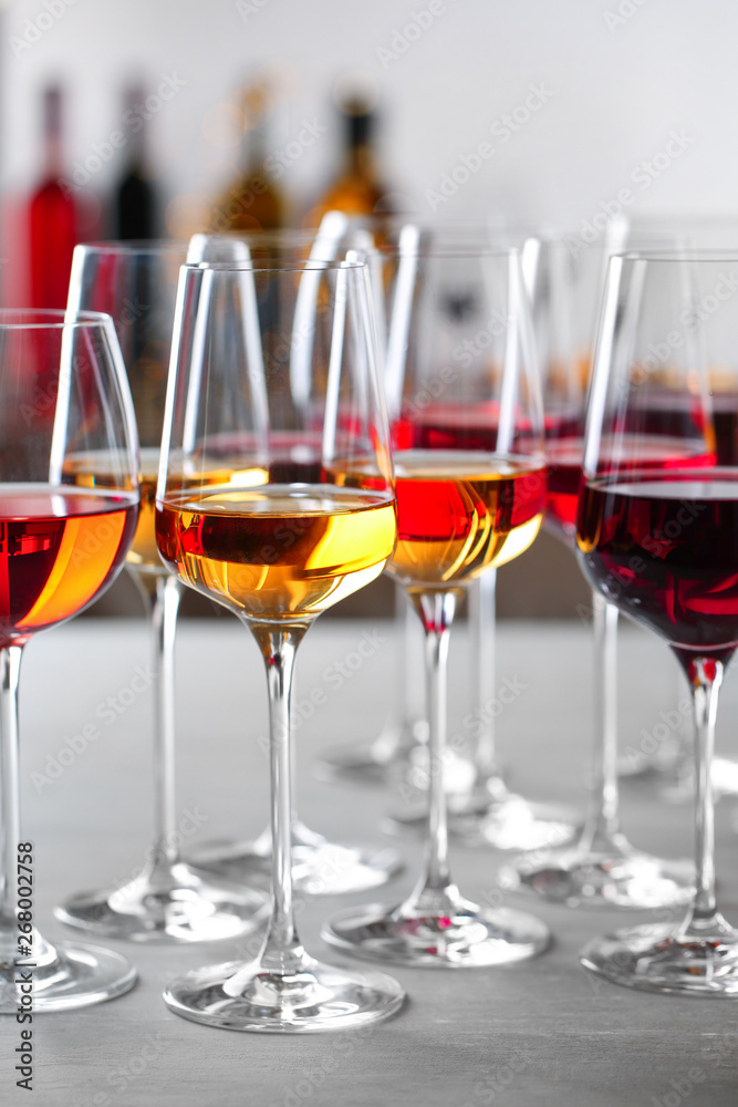 Glasses with different wines on table against blurred background