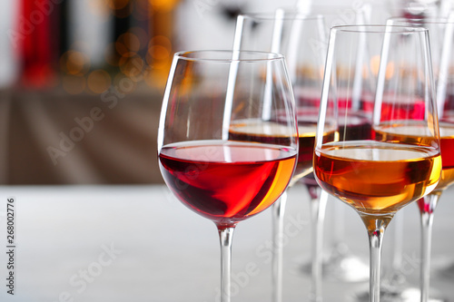 Glasses with different wines on blurred background, closeup. Space for text