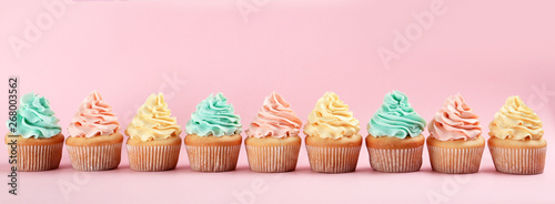 Photo Row of delicious cupcakes on color background, space for text