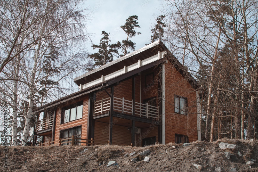 The concept of a country holiday. Wooden house on the lake covered with ice and snow