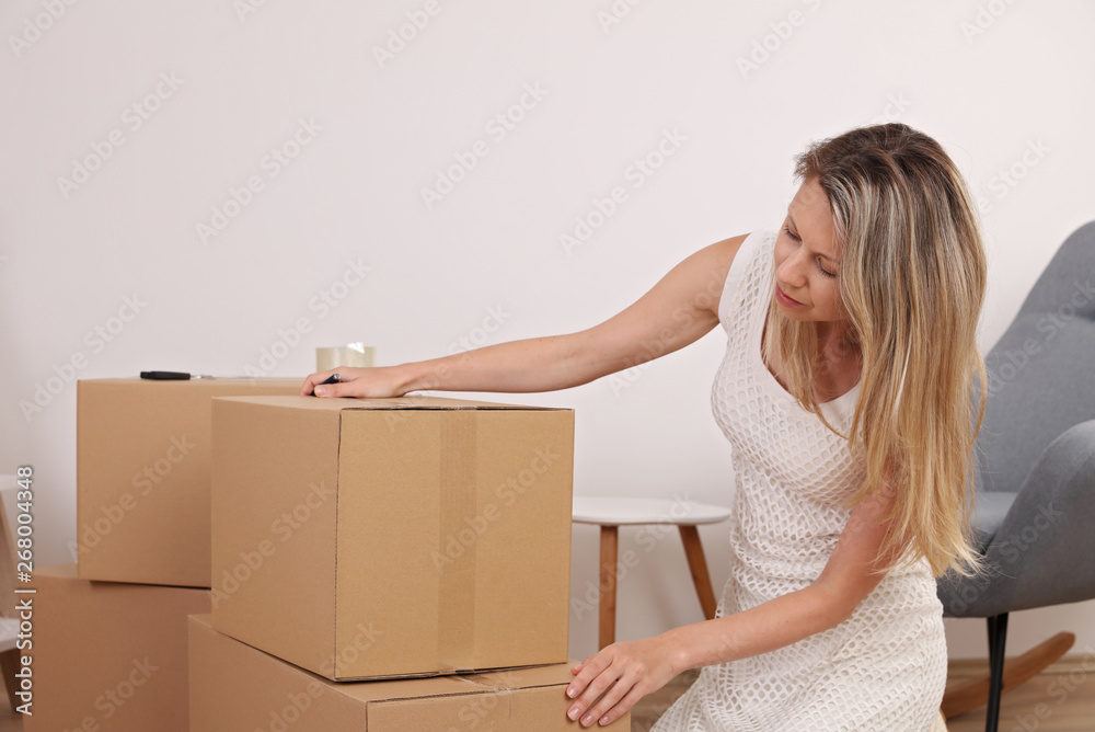 Moving in and out. Woman packing and labeling moving box at home Moving in and out. Woman packing and labeling moving box at home