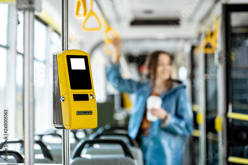 Yellow ticket machine in the modern tram with female passenger on the background
