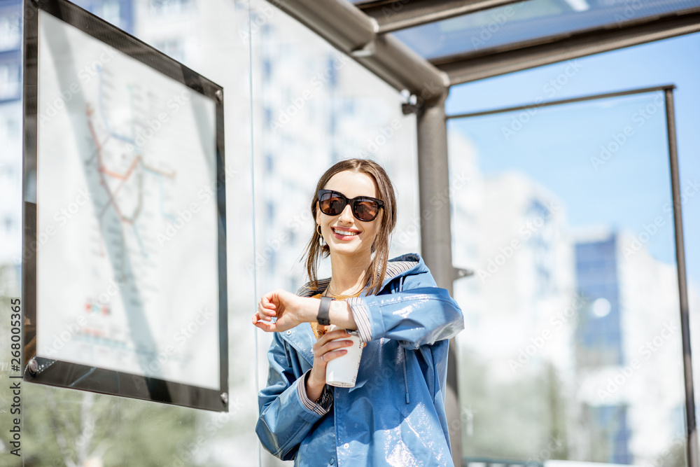 Young woman checking time while standing at the tram station outdoors