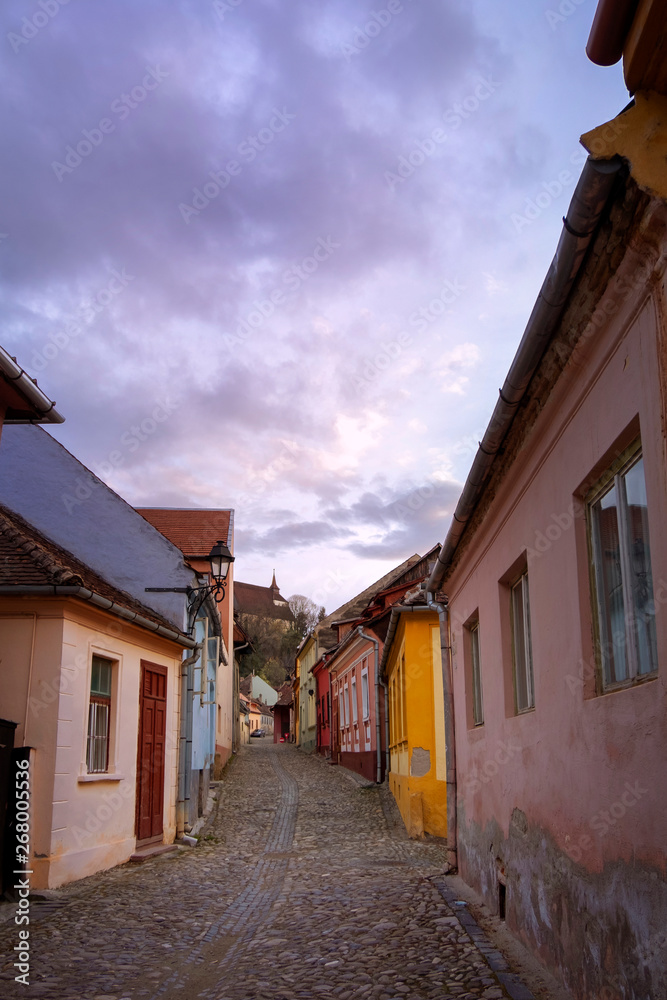 Street in Sighisoara with colorful houses at dusk.