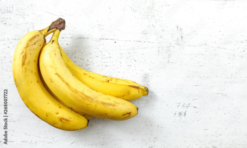 Bunch of bananas on white working board, space for text right Bunch of bananas on white working board, space for text right