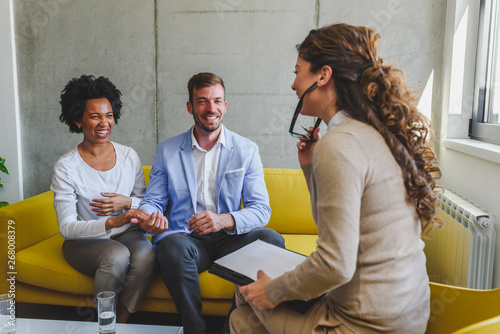 Young diverse married couple talking to their agent, advisor,therapist or sales representative photo