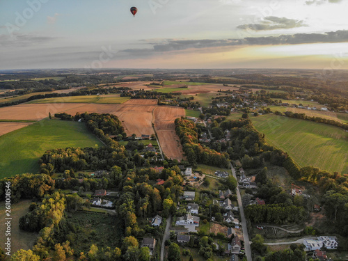 Hot air balloons in the sky of Walloon over beautiful farmland landscape. Colorful hot air balloons flying over the valley during sunset time. Belgium