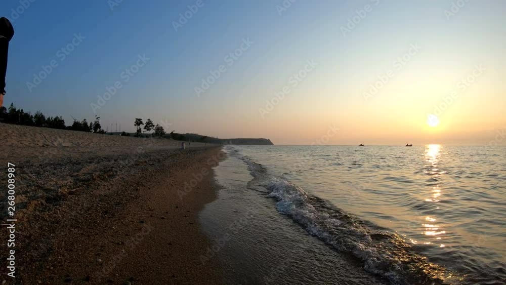 Man walks along the shore of lake Baikal at sunset. Slow motion Man walks along the shore of lake Baikal at sunset. Slow motion