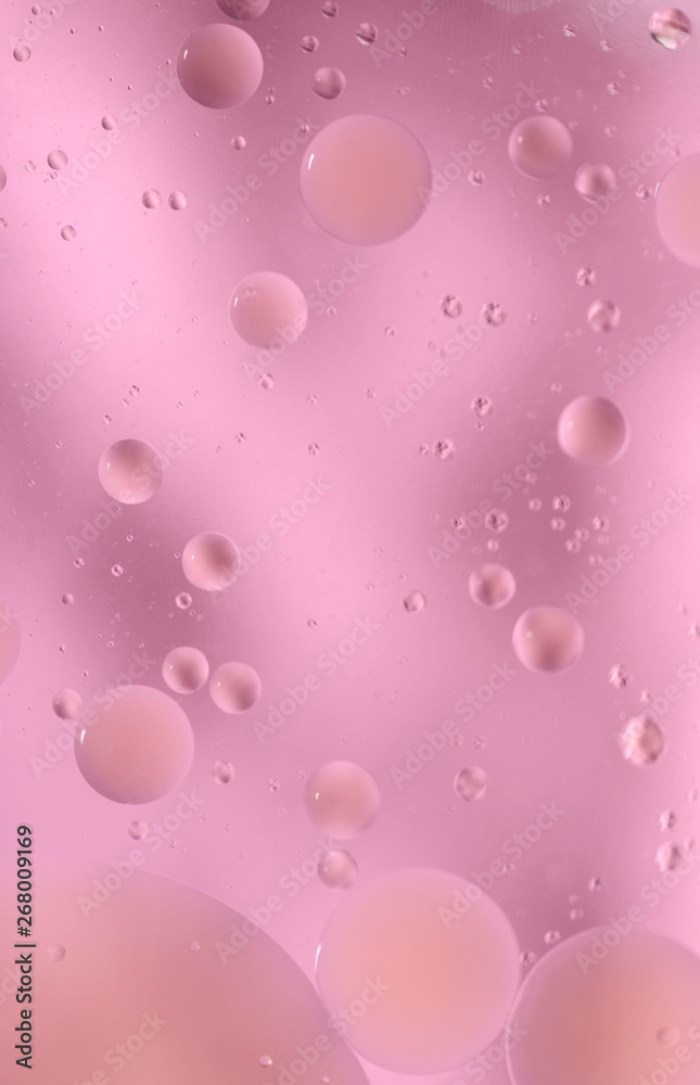 Drops of oil in water on a colored background. Bright background with pink circles of different sizes. Blur, vertical, place for text, monophonic. Design concept.