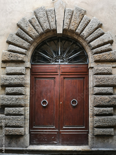Ancient wooden portal with carved stone arch of an Italian medieval fortress.