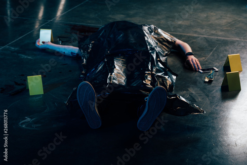 covered corpse near evidences on floor at crime scene