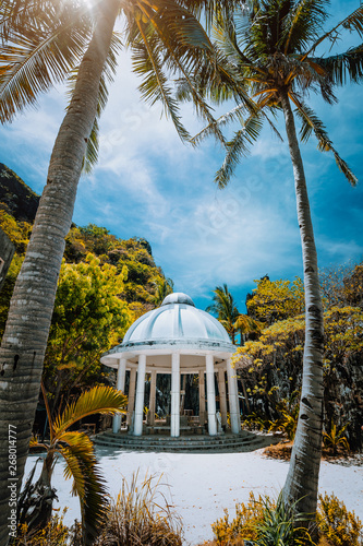 Fototapeta Abandoned Matinloc Shrine between two palm trees at the western coast of Matinlo