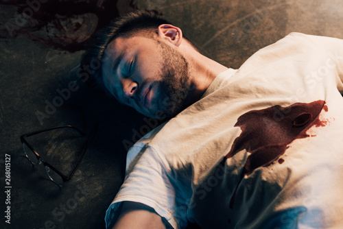Foto dead man with blood on t-shirt on floor at crime scene