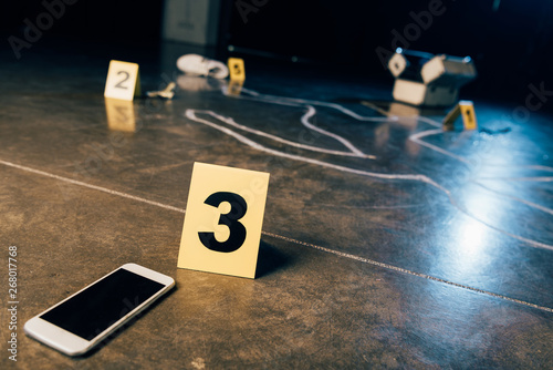 chalk outline, smartphone with blank screen and evidence markers at crime scene