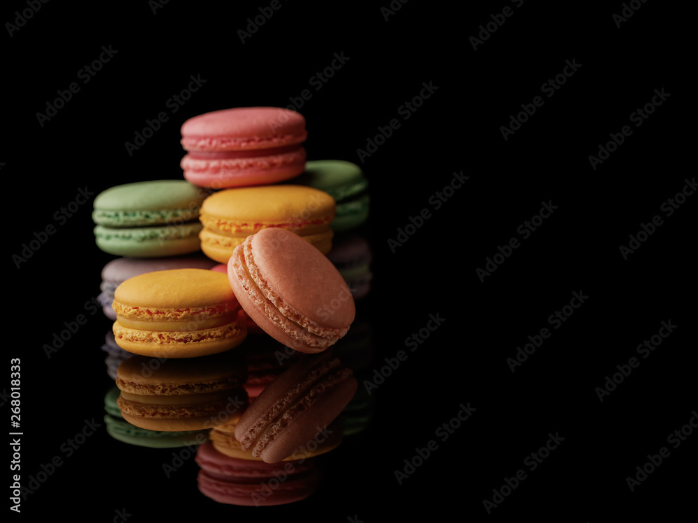 Obraz premium Multi-color macarons on the black background. Side view. Blank space.