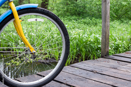 Bicycle wheel. Bicycle on the background of a wooden bridge in the forest