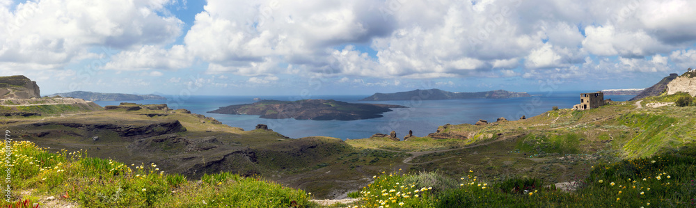 Summer sunny morning on the island of Santorini, Greece. Blue sea, blue sky with clouds against the background of the island. Euro trip. .Volcanic island in the Aegean Sea. .Panorama. Summer sunny morning on the island of Santorini, Greece. Blue sea, blue sky with clouds against the background of the island. Euro trip. .Volcanic island in the Aegean Sea. .Panorama.