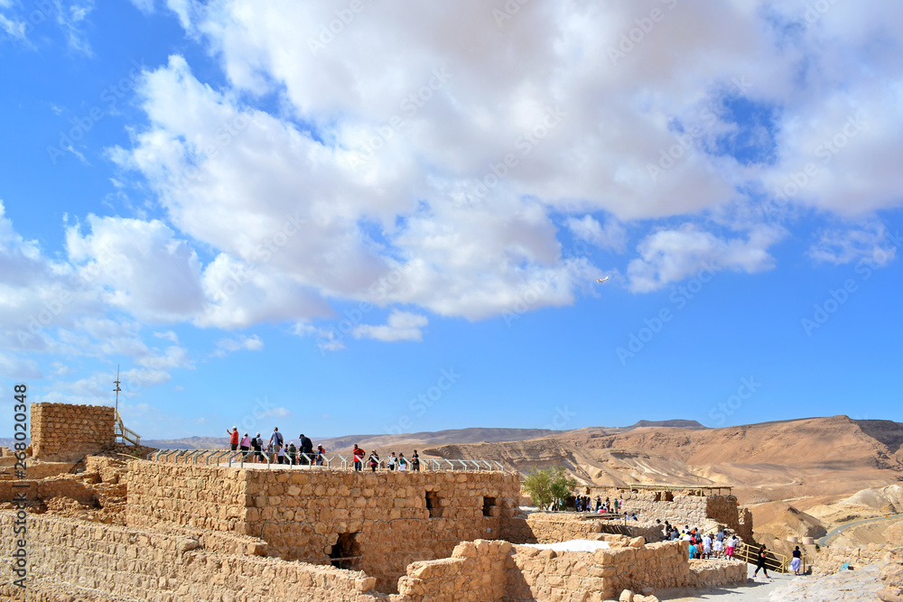 Tourists visit the ruins of ancient fortress,  strategic location high on a flat plateau above the Dead Sea 