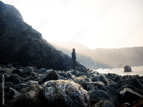 man standing on rocks facing cean photo