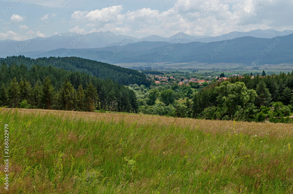 Springtime scene with glade, forest and residential district of bulgarian village Alino in Plana mountain near Rila  and Verila mountains, Bulgaria 