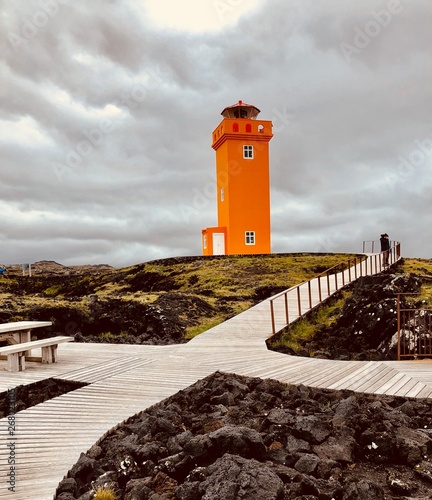 orange lighthouse under nimbus clouds