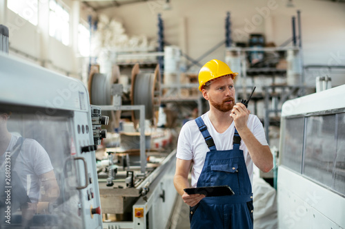 Man in uniform at factory talking on walkie-talkie