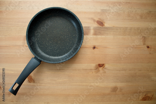 empty black pan on brown wooden background top view