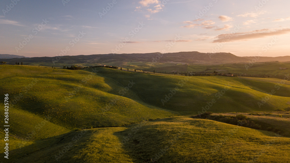 Colline con campi di grano coltivati in val d'orcia Toscana al tramonto