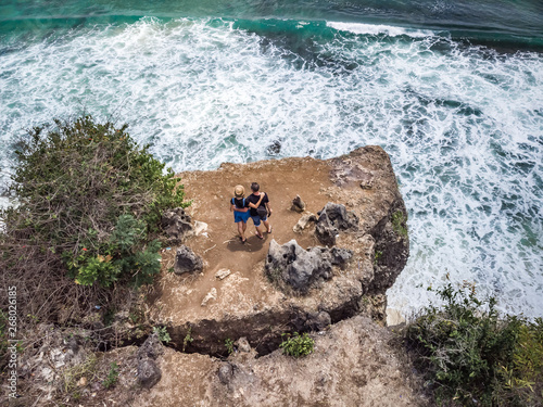 two people standing on cliff overlooking big waves photo