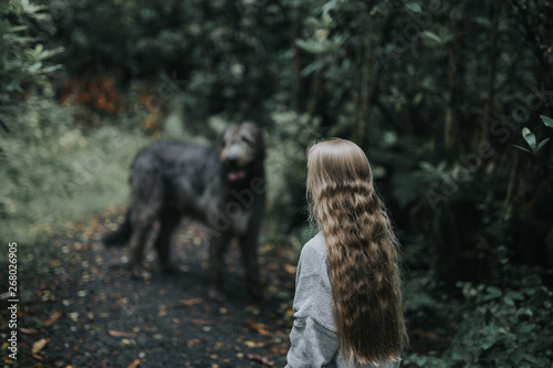 woman in gray sweater facing on gray dog near trees