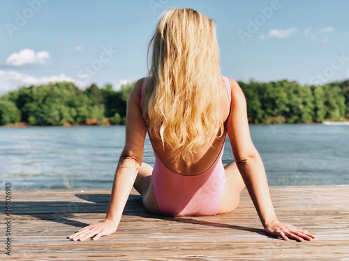 woman in pink bikini sitting on wooden board in front of body of water during daytime photo