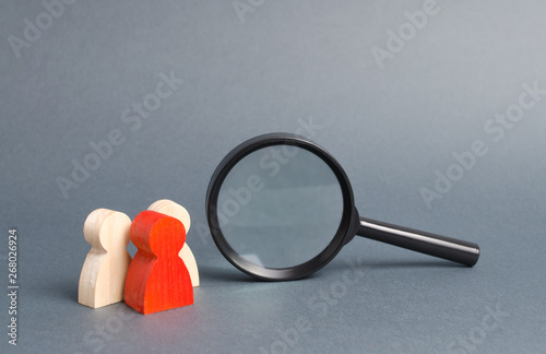 The leader and his team stand near a magnifying glass on a gray background. Human resources, management. The concept of the search for people and workers. Search for vacancies and work.