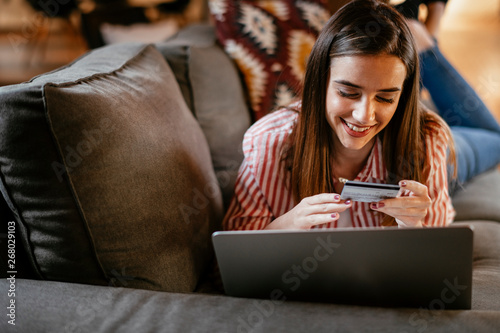 Young woman at home makes a purchase on the Internet on the laptop with credit card