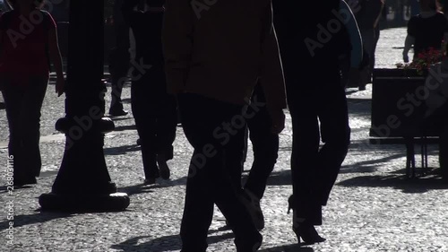 People walking on the city street sidewalk in black and white. Silhouettes of walking multiple people legs on cobblestone ground. A urban landscape concept.