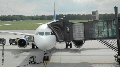 Landing on the plane. People pass through the jetbridge aboard an unrecognized airline. Slow Motion.