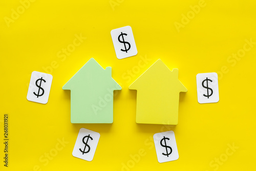 Buy house with figure and dollar on office desk mint green yellow background top view